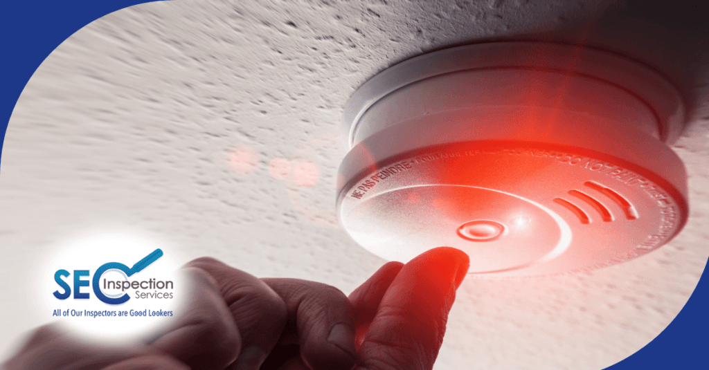 Hand testing a smoke detector with a glowing red light