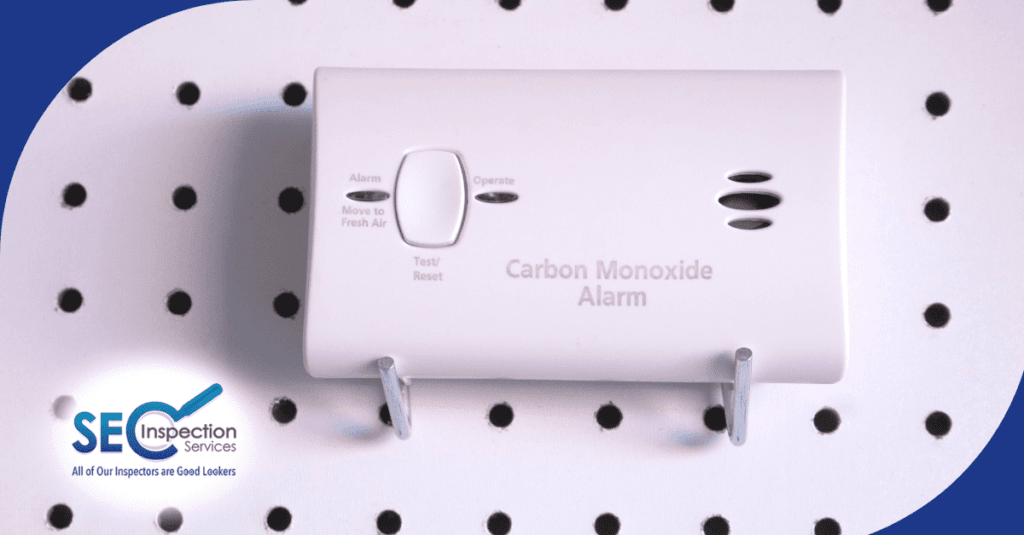 Wall-mounted carbon monoxide alarm displayed on a perforated board
