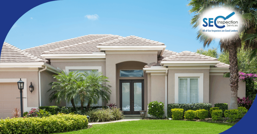 Single-story beige home with tile roof, palm trees, and neatly trimmed landscaping.