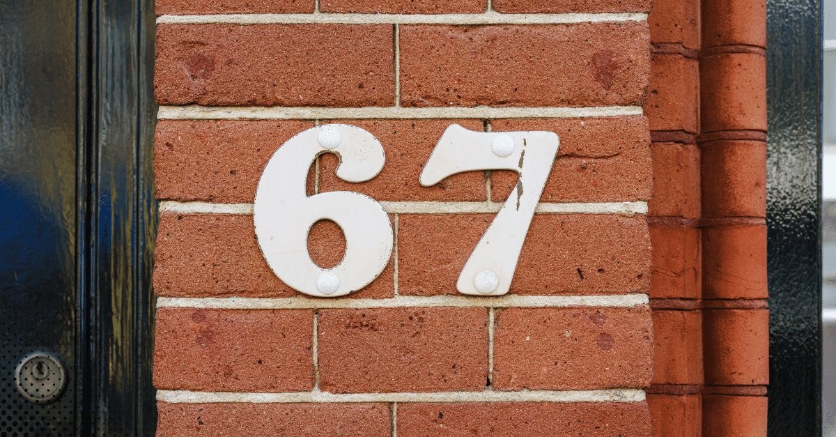 White house number 67 mounted on a red brick wall