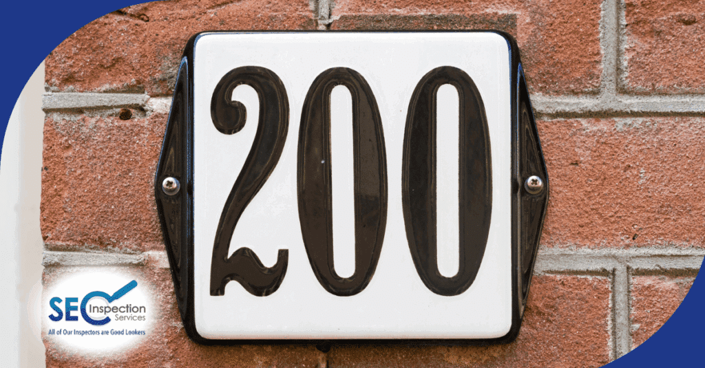 Black house number 200 on a white plaque mounted to a brick wall