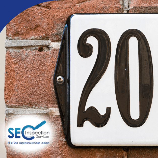 Black house number 200 on a white plaque mounted to a brick wall