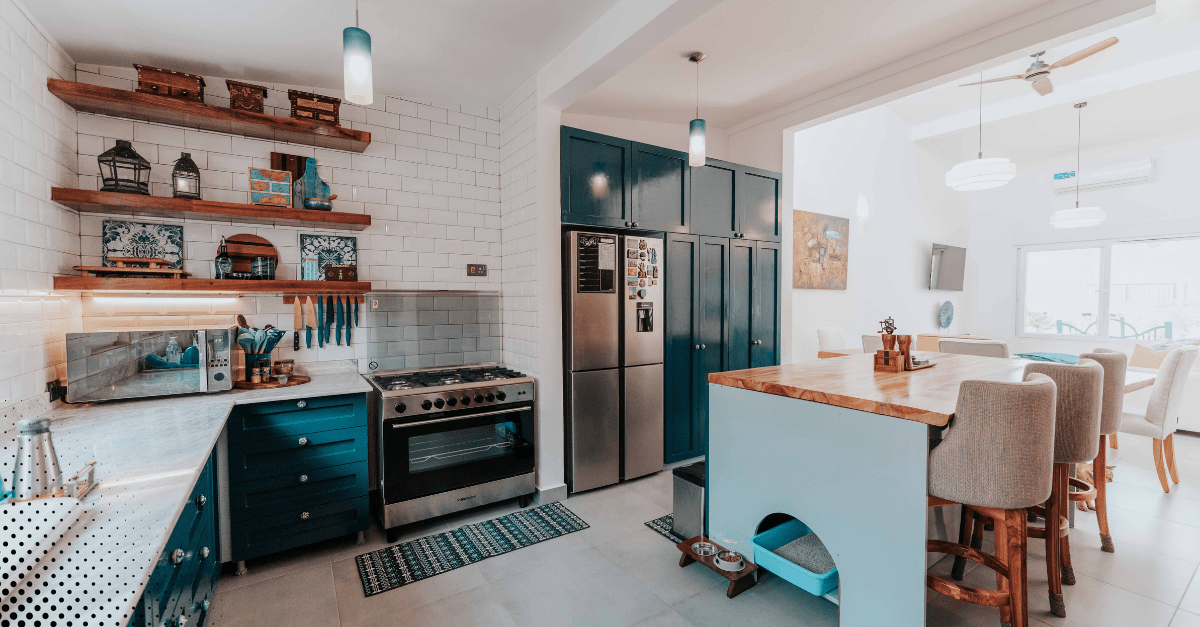 Modern kitchen with teal cabinets, a sleek stove, and open shelves showcasing cooking essentials.