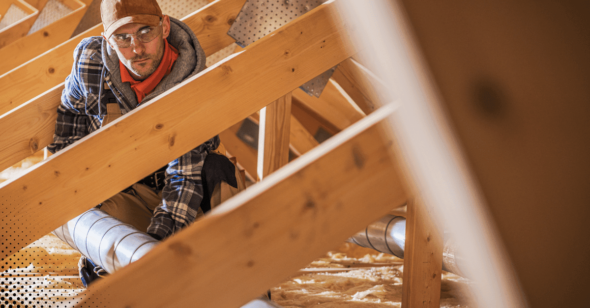 Inspector reviewing attic ductwork and insulation.